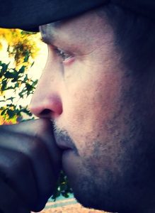 A man with his hand to his face and nose resting on the side of his chin.