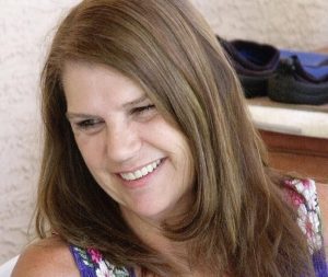 A woman with long brown hair smiles for the camera.