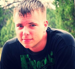 A man with a mohawk haircut sitting in the grass.