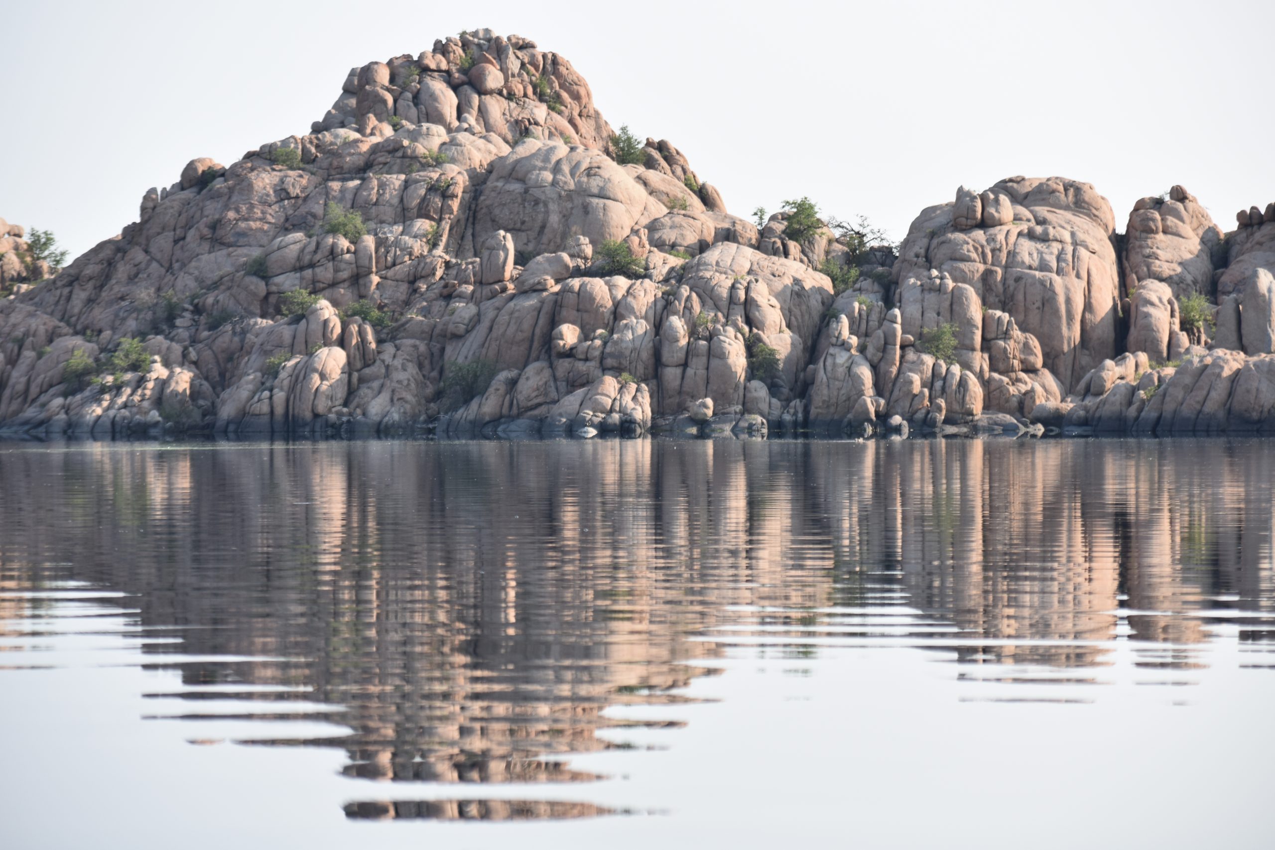 A large rock formation is reflected in the water.