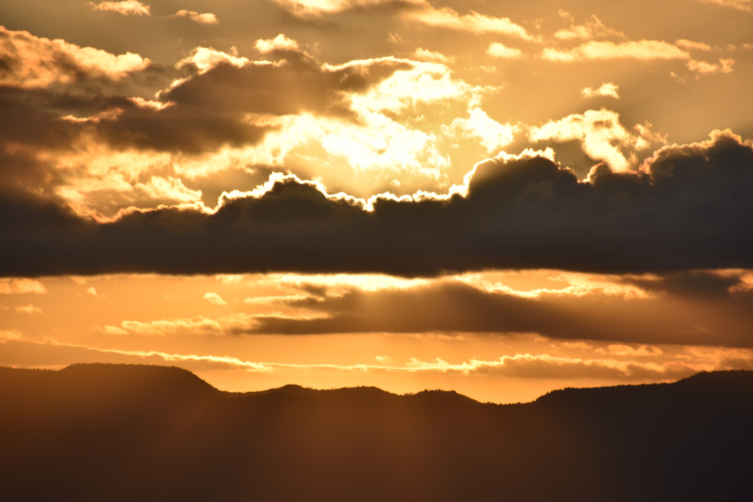 A sunset with clouds and sun beams in the sky.