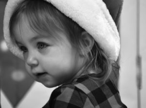 A little girl wearing a hat and plaid shirt.