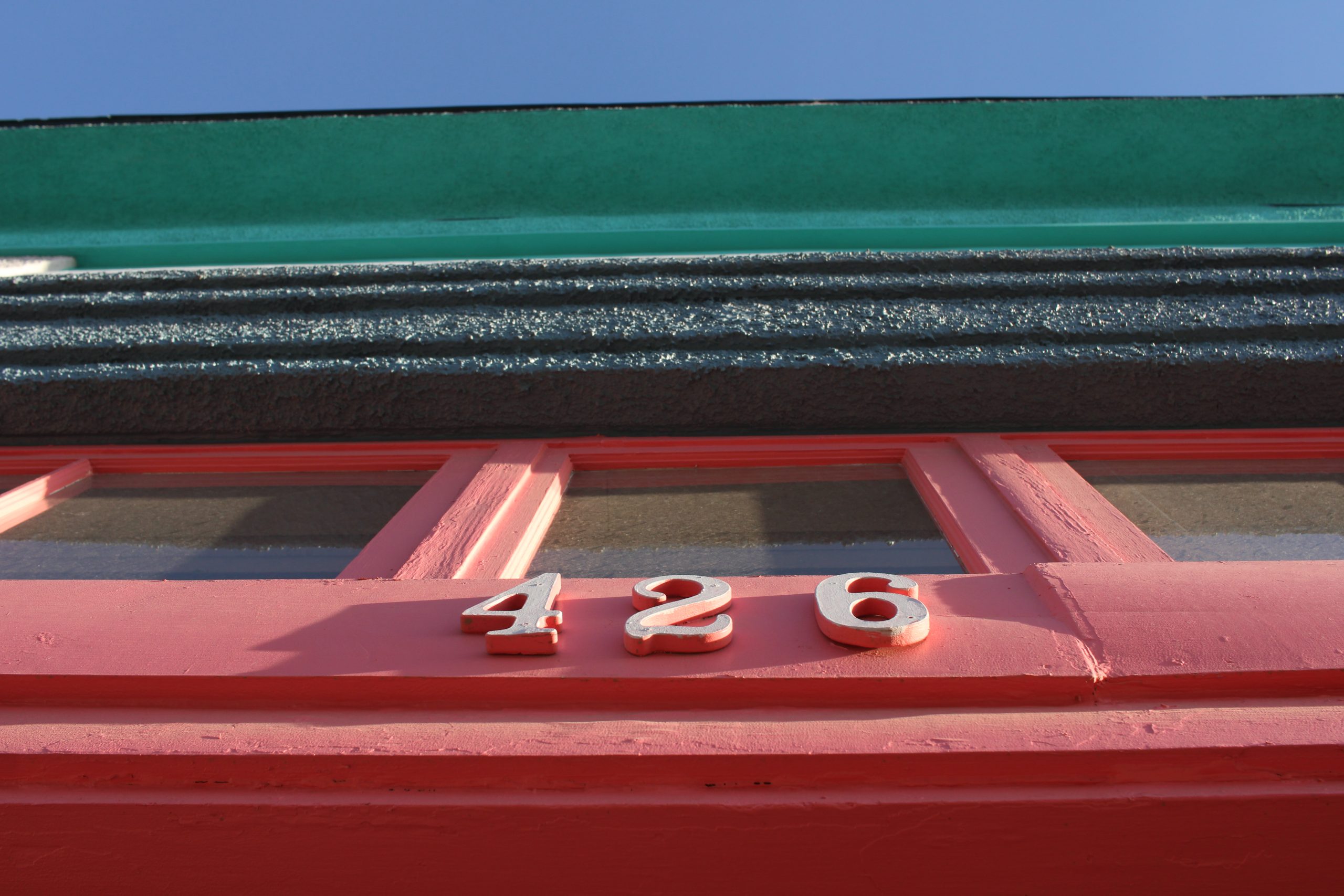 A close up of the number 4 2 6 on top of a red door.