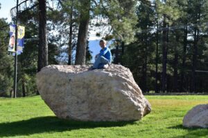 A person sitting on top of a large rock.