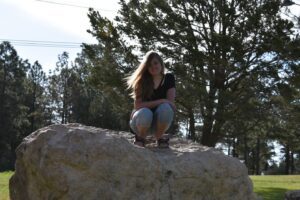 A woman sitting on top of a rock.