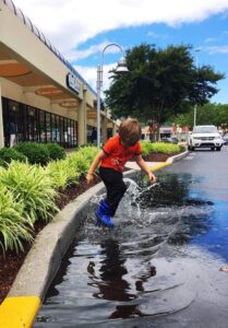 A boy in blue boots is playing with water