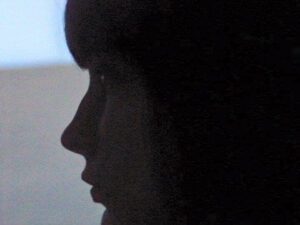 A woman 's face is shown in the dark.