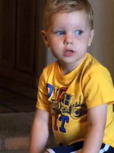 A young boy in yellow shirt sitting on floor.