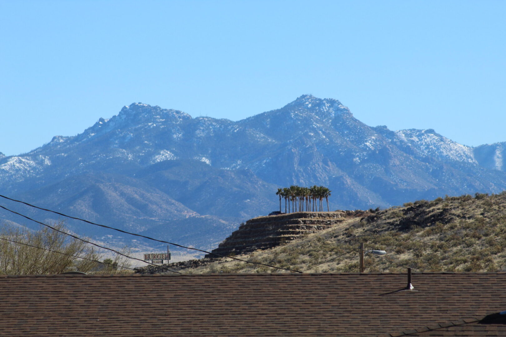 A person standing on top of a hill near some mountains.