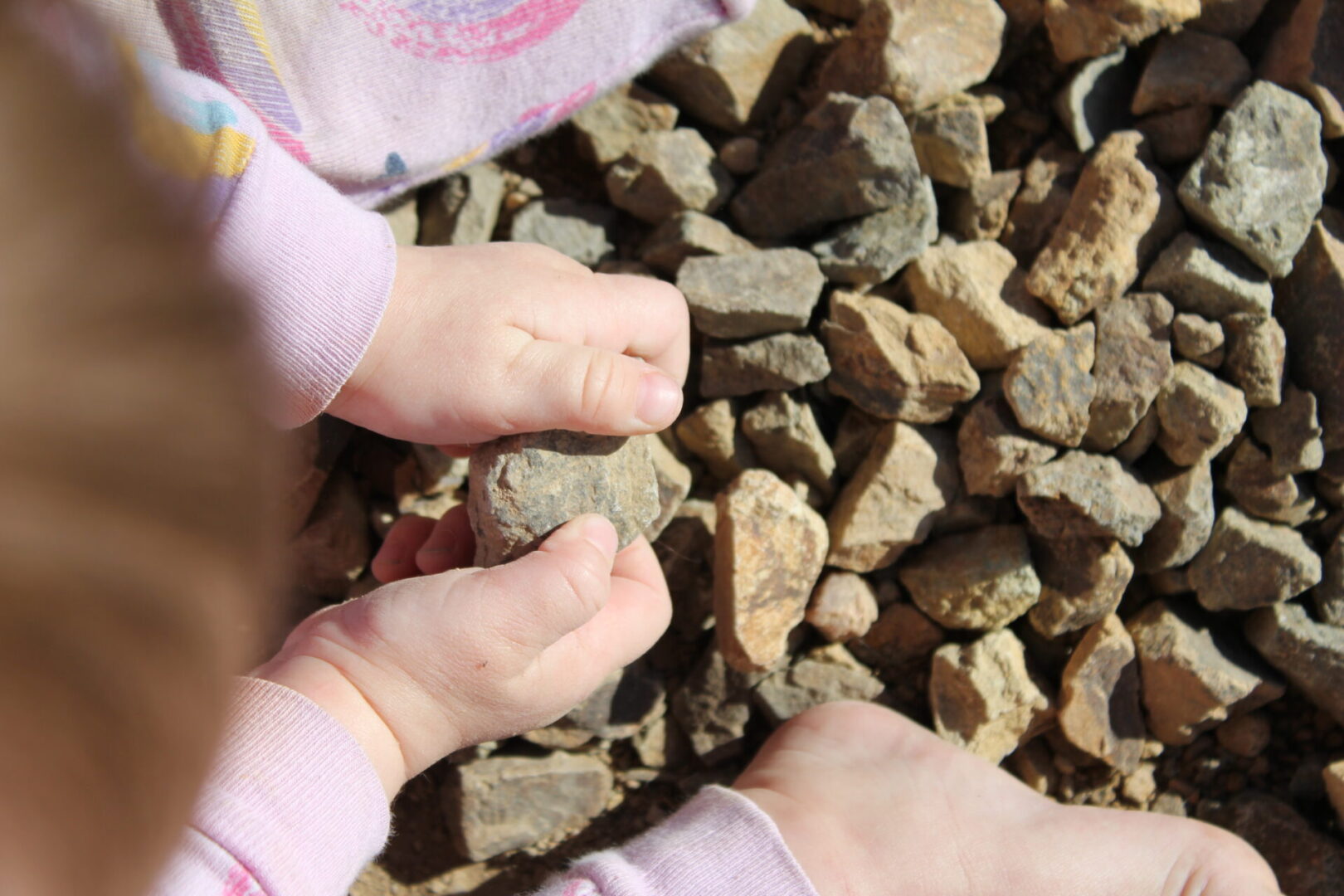 A baby 's feet are in the dirt.