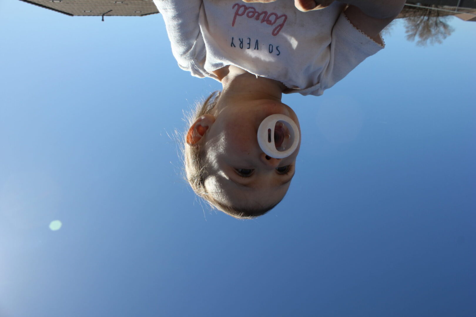 A child hanging upside down with an object in his mouth.