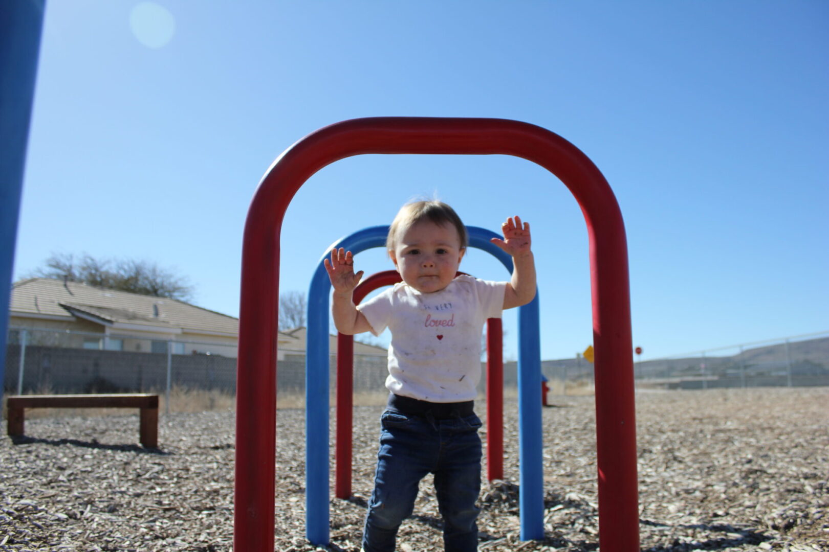 A toddler is playing in the sand at an outdoor playground.