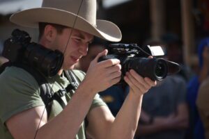 A man in a cowboy hat holding a camera.