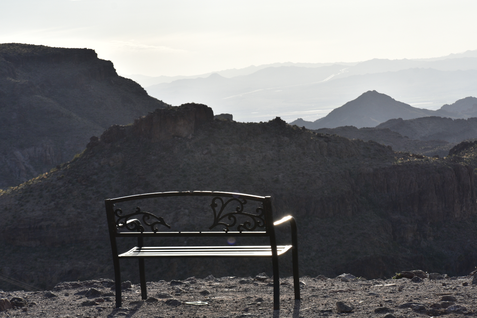 A bench on top of a mountain with mountains in the background.