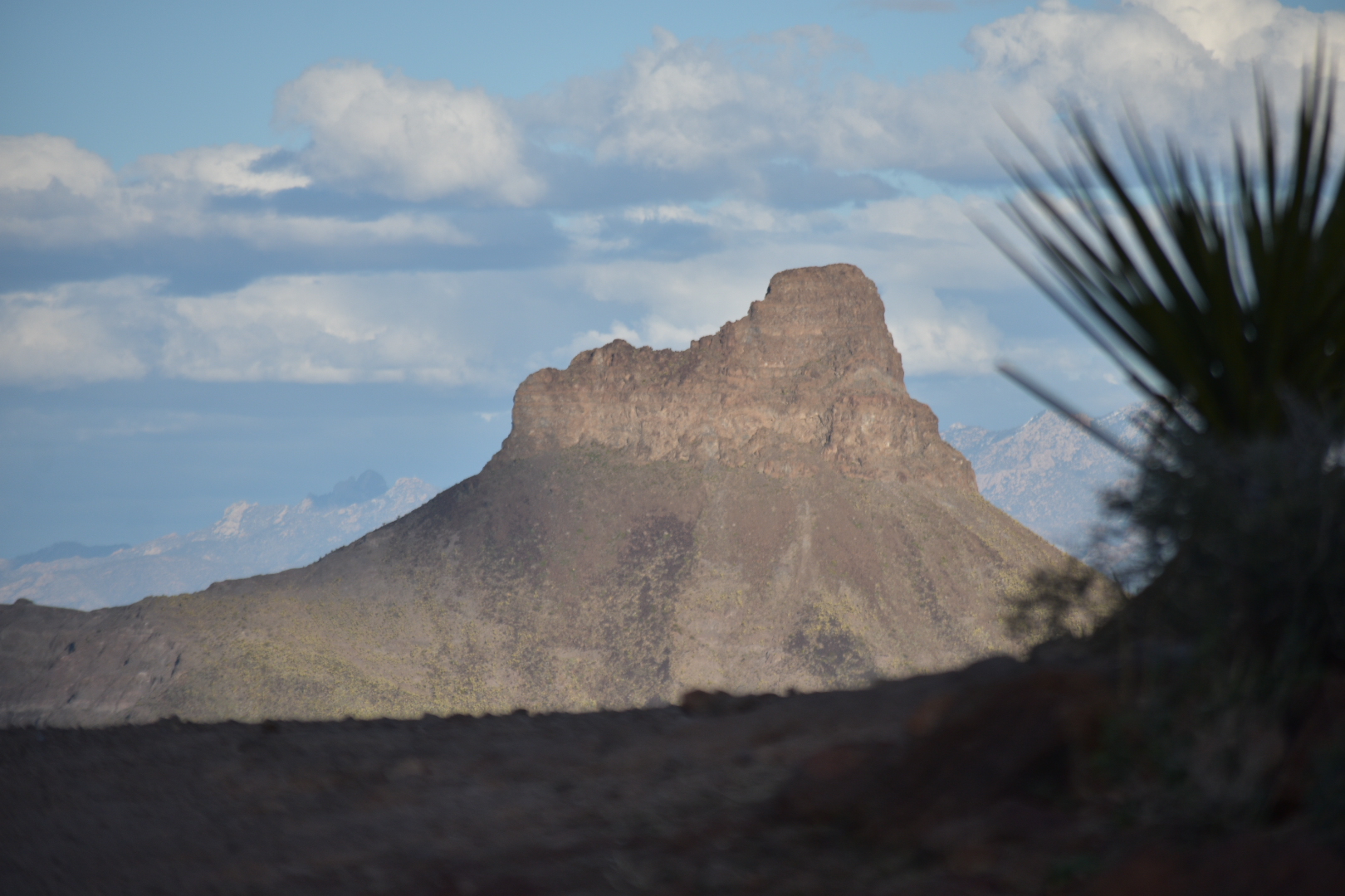 A mountain with a sky background and some clouds