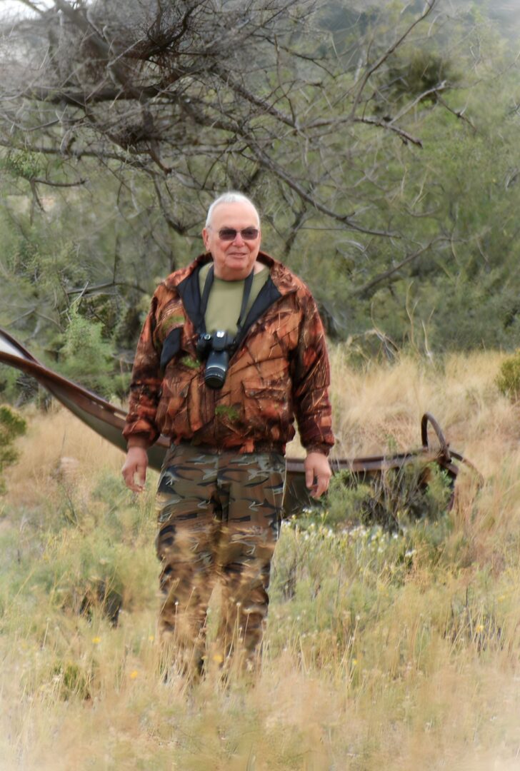 A man in camouflage holding an arrow and wearing a camera.