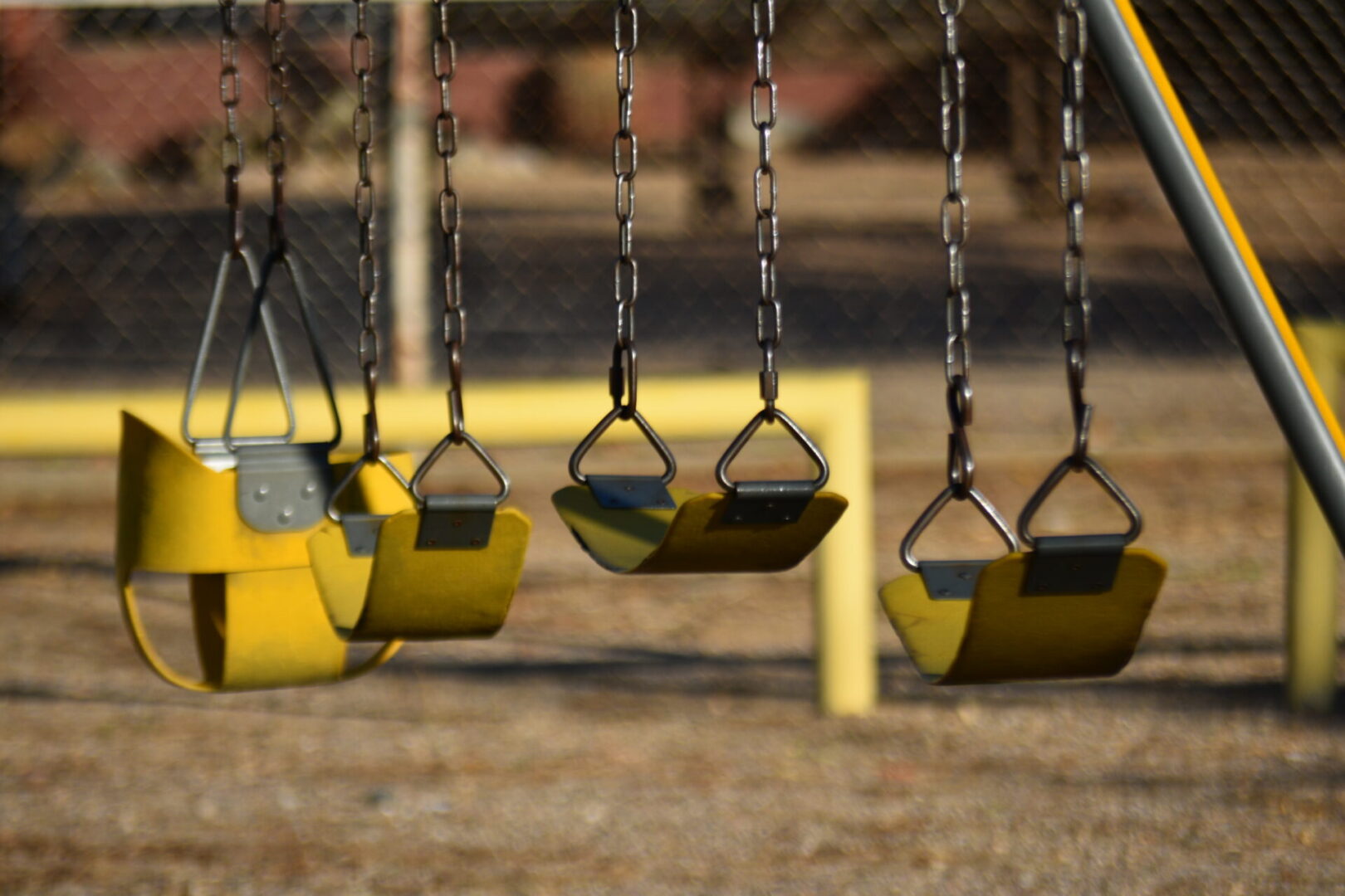 A group of swings hanging from chains in the park.