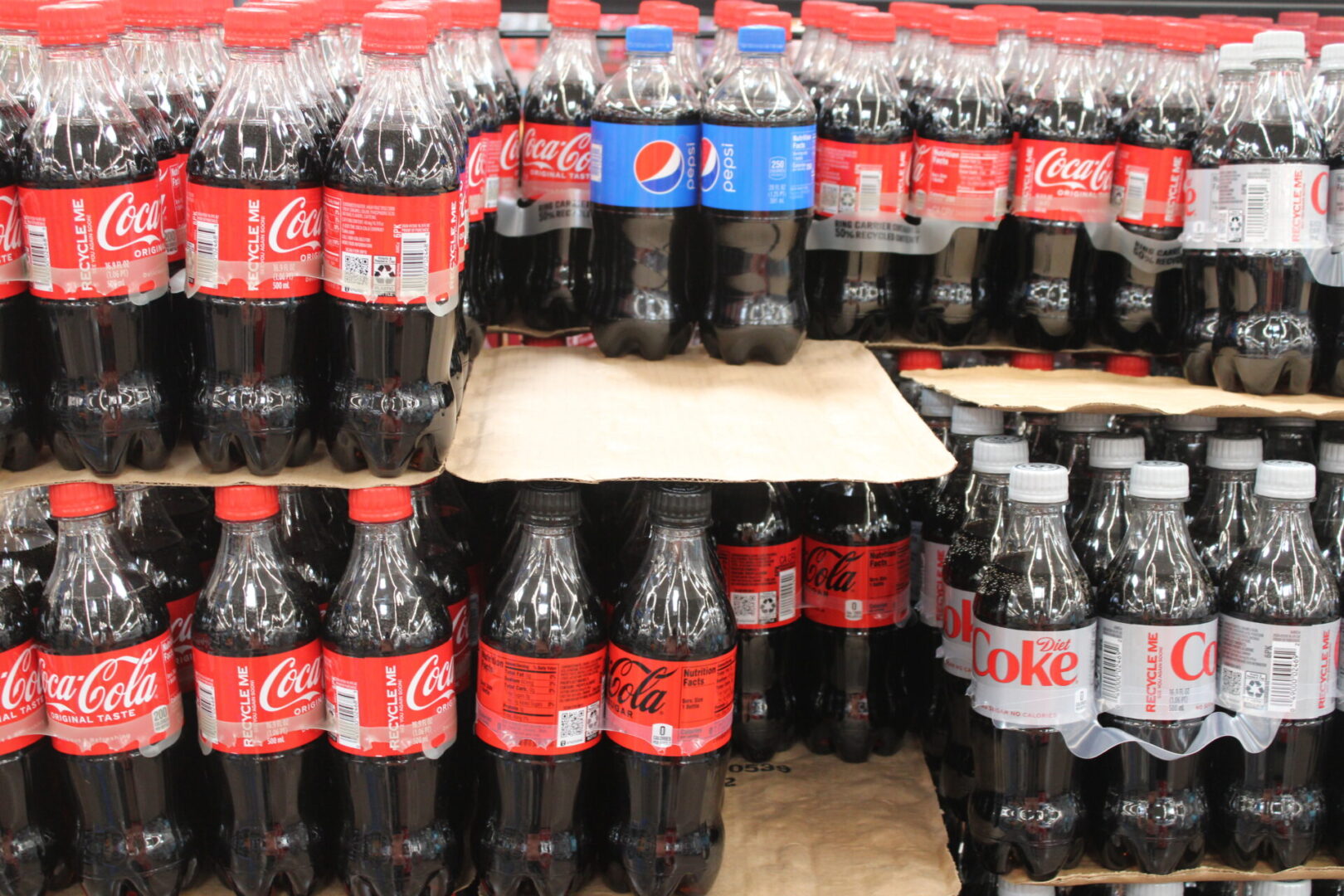 A large amount of soda bottles are stacked on top of each other.