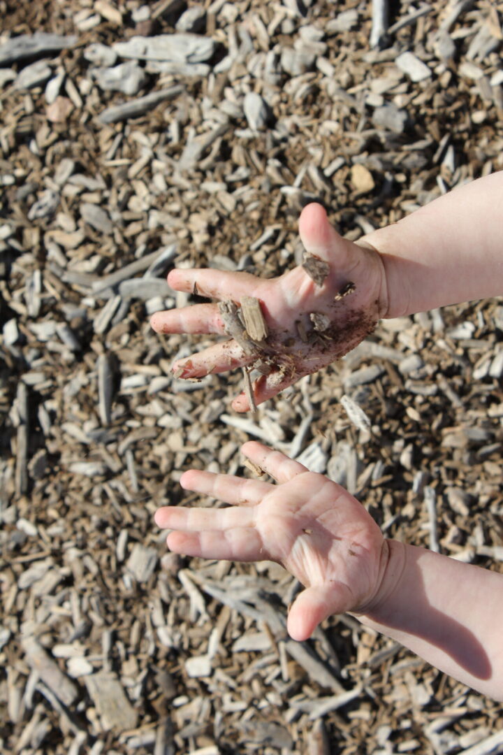 A person 's hands in the dirt with their fingers crossed.