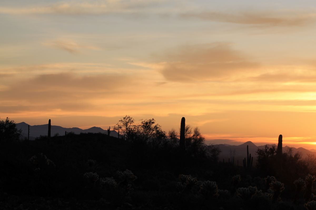 A sunset with the sun setting over mountains.