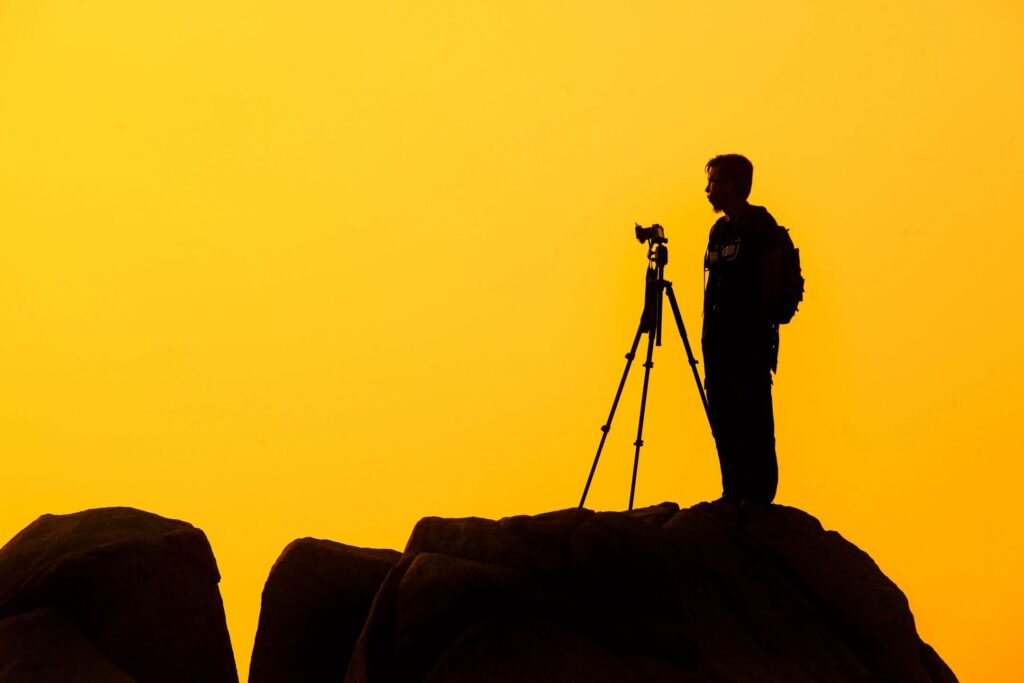 A man standing on top of a hill with a camera.