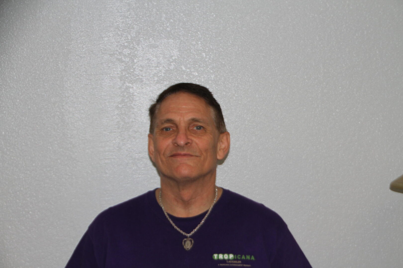 A man in a purple shirt is smiling for the camera.