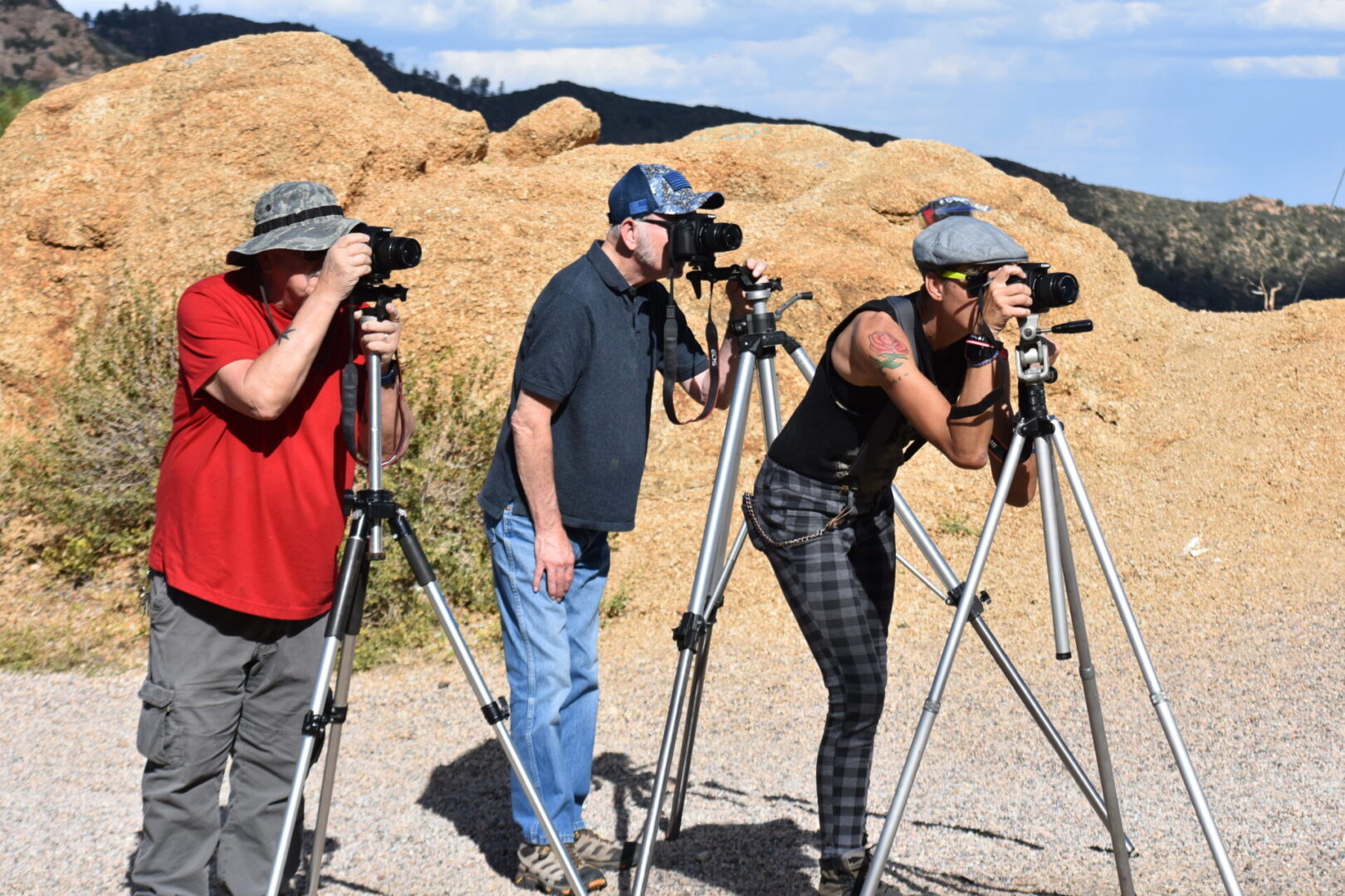 Three people are taking pictures on a tripod.