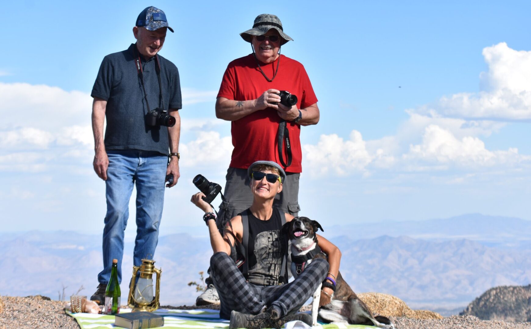 A group of people with cameras and bottles on the ground.